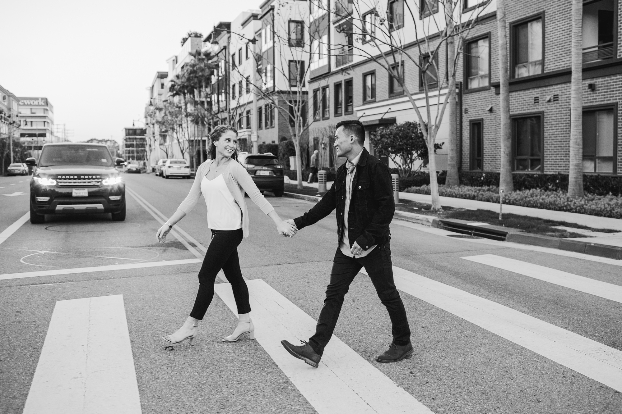 engagement photo of couple holding hands and walking in a crosswalk - black and white photo