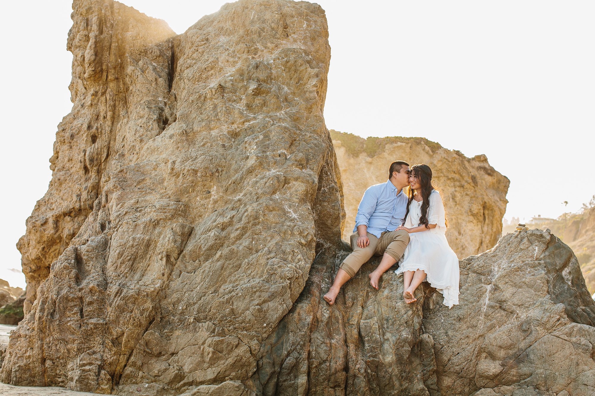 couple sitting on rock in malibu california